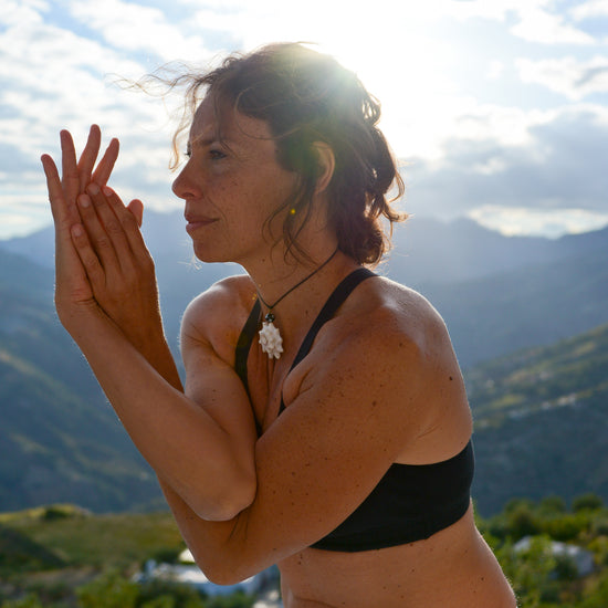 Foto de la profesora de yoga Marina,con un telón de fondo montañoso y un sol radiante